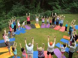 Time in nature is essential for mental health, people  standing in a circle, on grass, with their arms raised and smiling